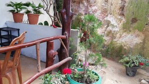Un escalier en bois menant à un balcon agrémenté de plantes en pot et d’un mur rustique.
