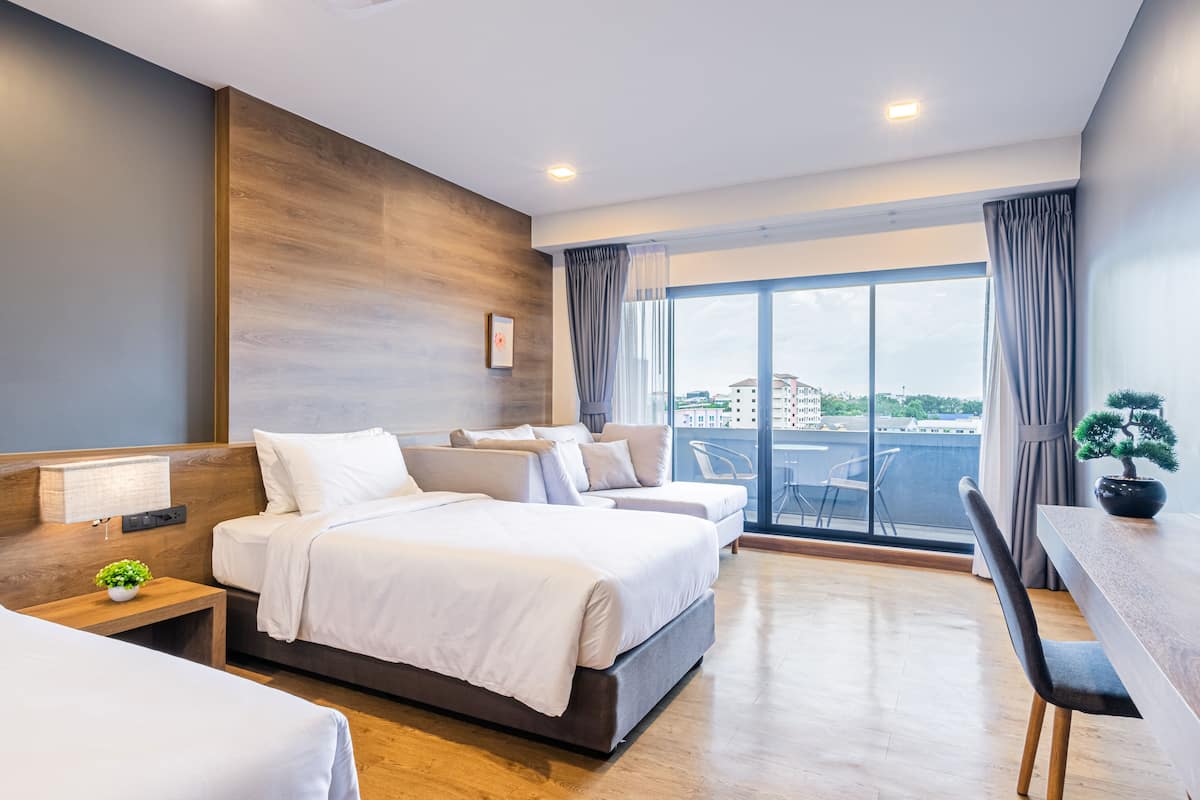 Een moderne hotelkamer met een groot bed, een kleiner bed, een bureau en een balkon met uitzicht.