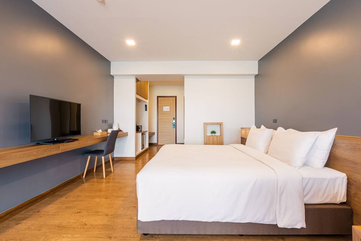 Een moderne hotelkamer met een groot bed, een bureau met een televisie en een klein zitgedeelte.
