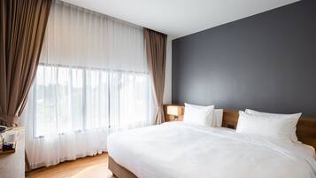 Un lit bien fait, avec du linge de lit blanc, une tête de lit en bois et une table de chevet avec une lampe.