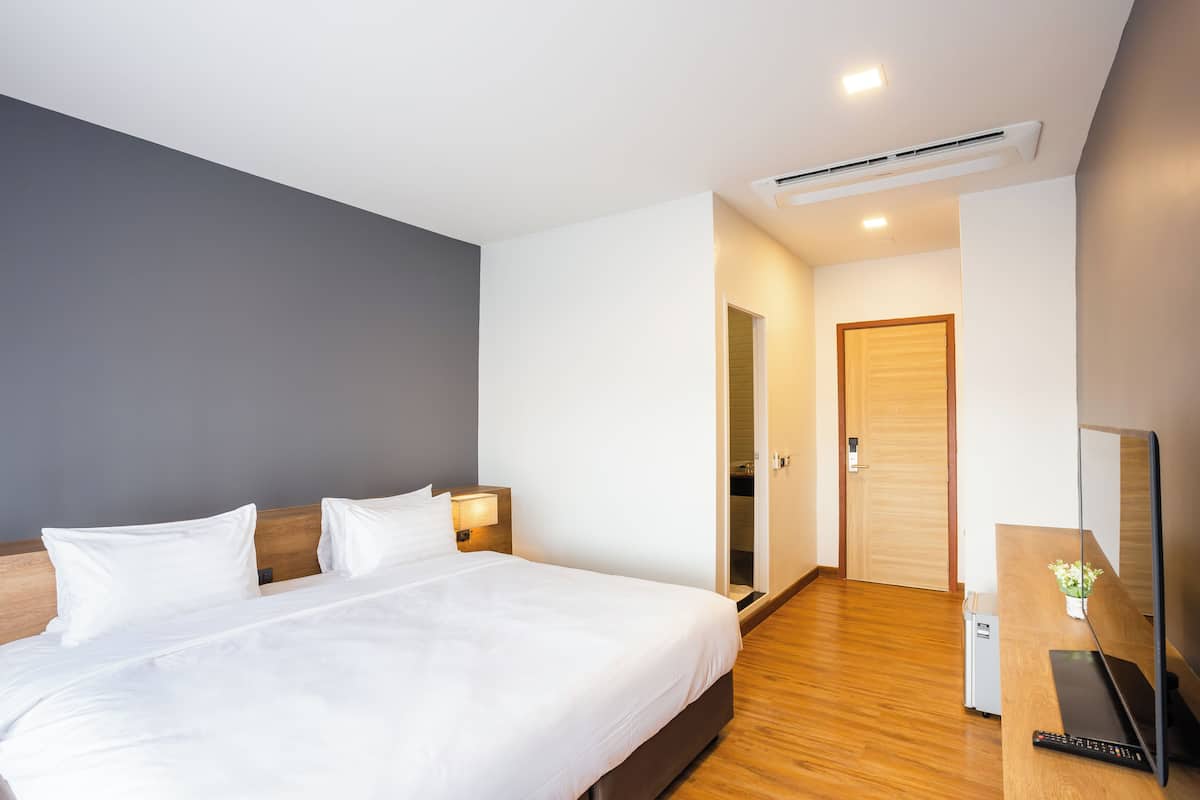 Een hotelkamer met een bed, nachtkastjes, een televisie en een bureau met een computer.