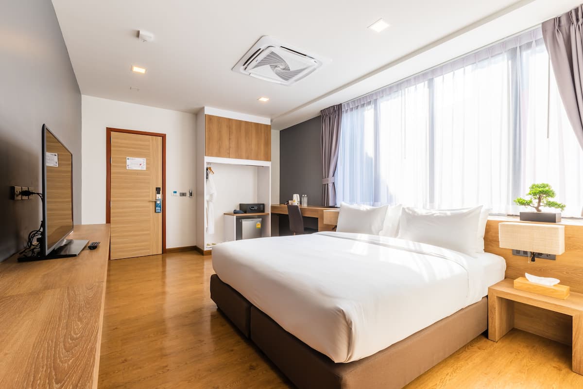 Een moderne hotelkamer met een groot bed, een bureau, een televisie en een kleine kitchenette.