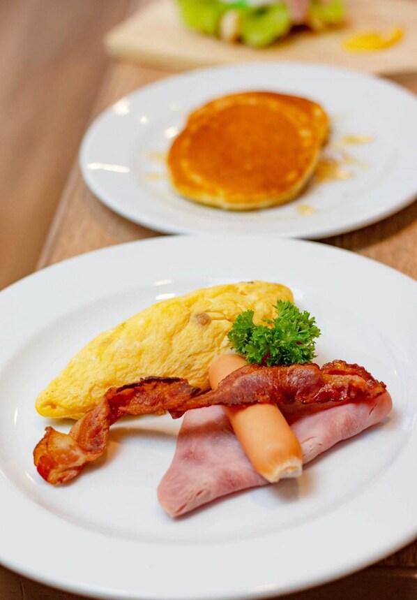 A breakfast plate with scrambled eggs, bacon, ham, and a garnish. - Icon Park Hotel Chiang Mai (Chiang Mai)
