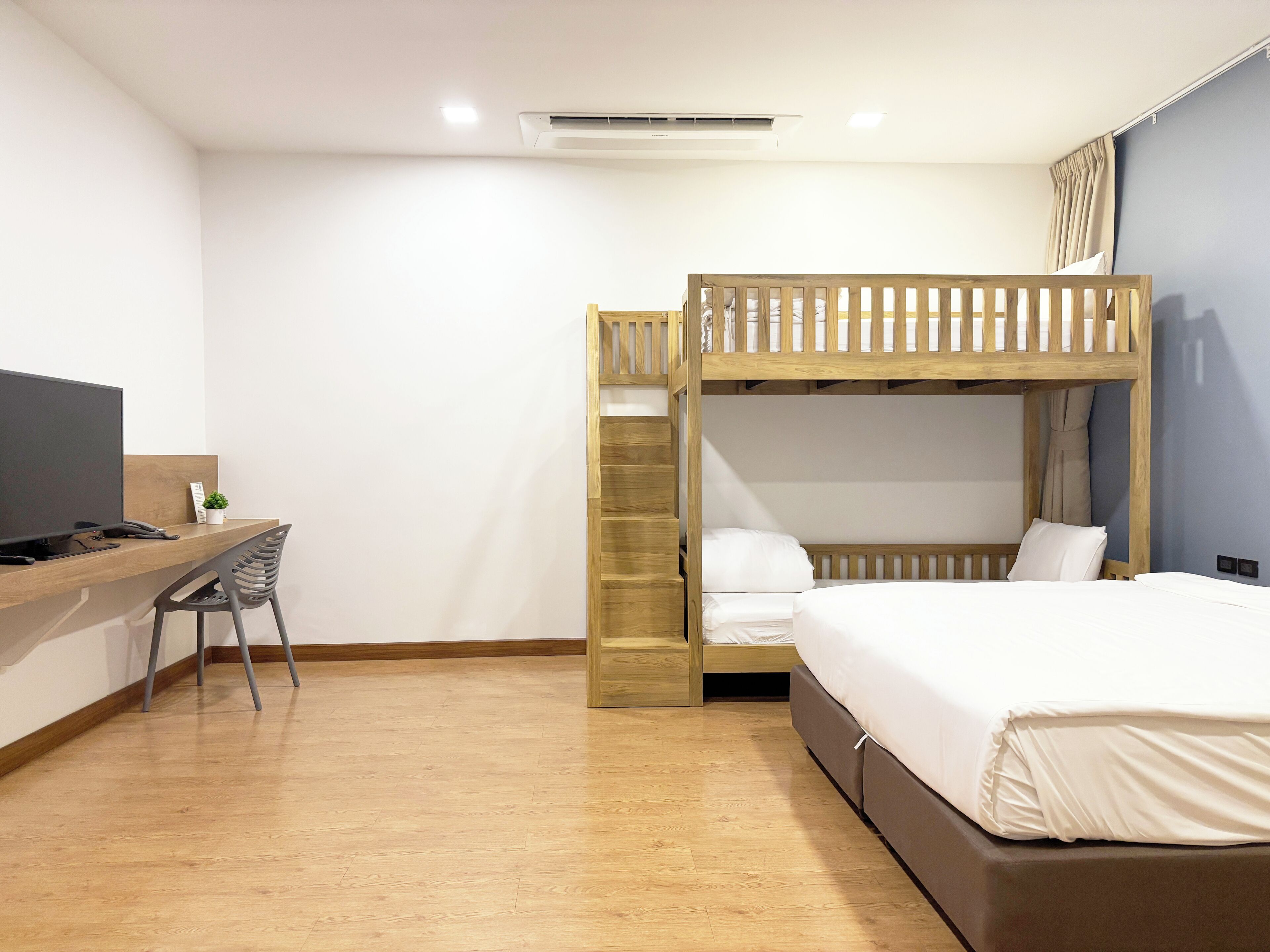 A room with a bunk bed, a desk with a computer, and a TV.