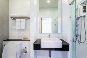 Un baño moderno con inodoro blanco, lavamanos con encimera negra y cabina de ducha con paredes de vidrio.