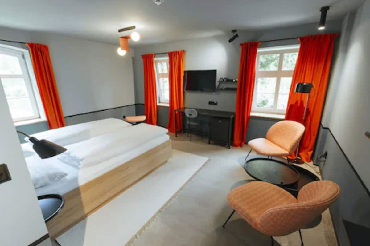 A modern hotel room with a bed, desk, chair, and a TV.