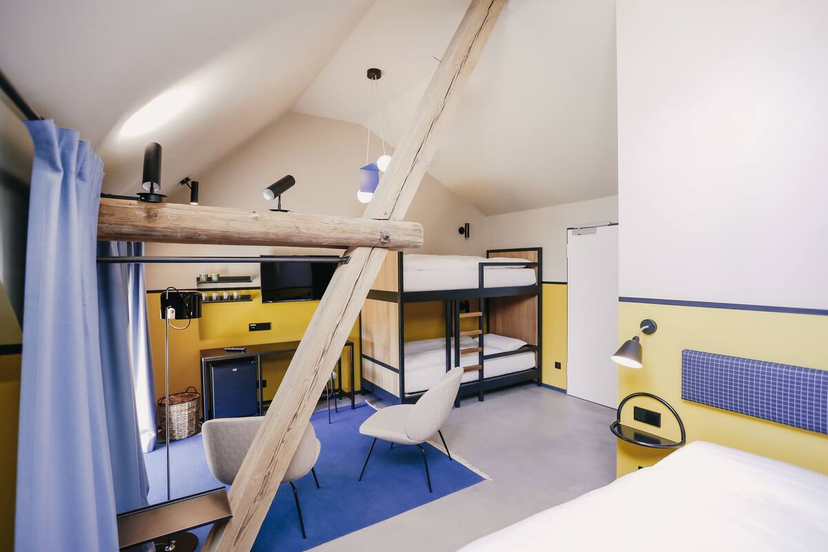 A compact room with bunk beds, a desk, a chair, and a small kitchenette.