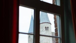 A window with a view of a building featuring a tower and a spire.