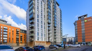 A multi-story hotel with balconies, a parking lot, and adjacent buildings. - Highlife Lexington Apartments (Slough)