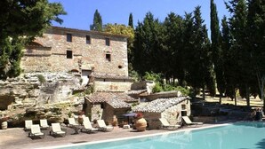 A stone building with a pool, surrounded by trees and a clear sky. - Verdidea - Aia Vecchia (Asciano)