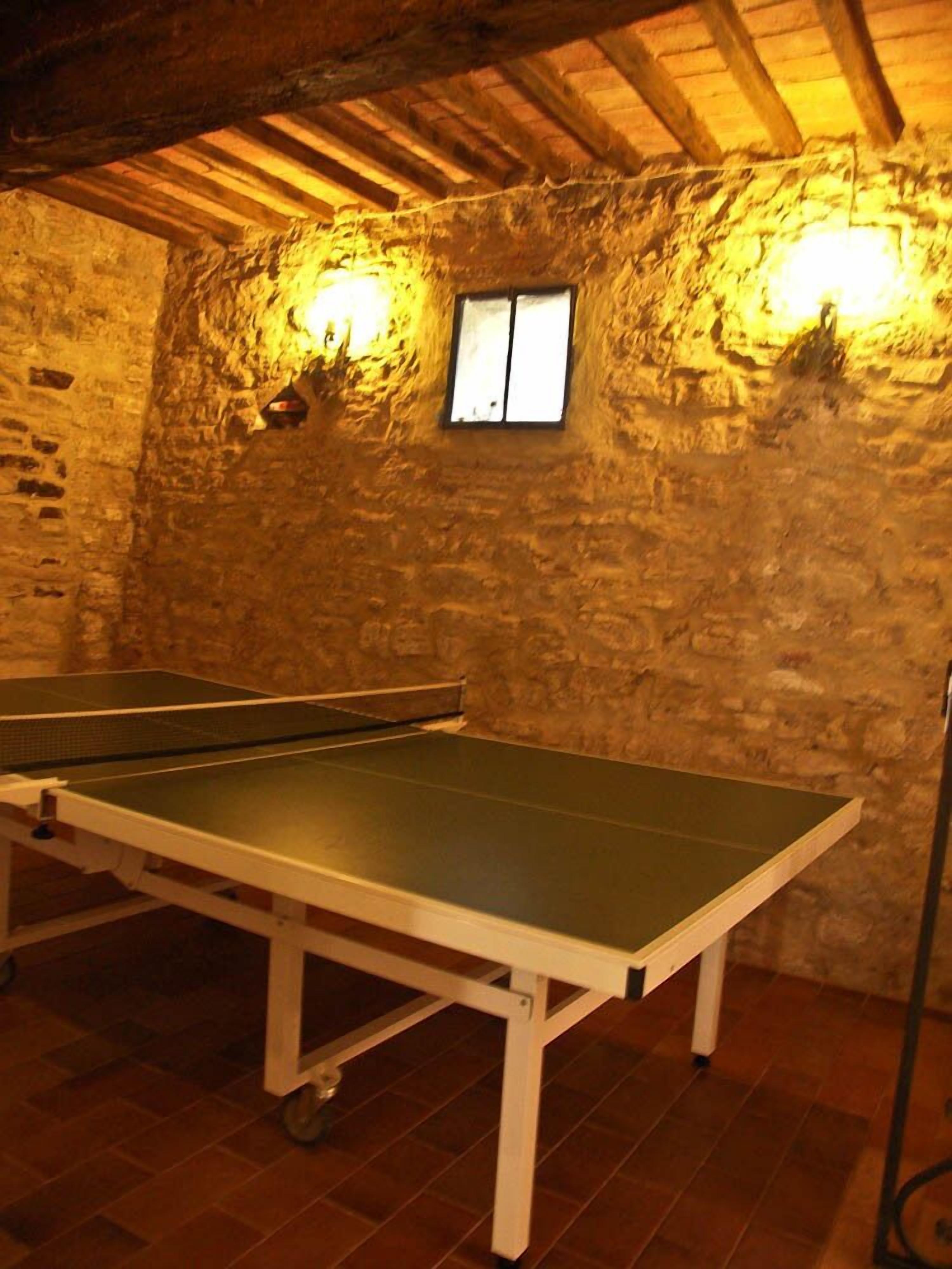 Ein Tischtennis-Tisch in einem Raum mit Steinwänden und Holzbalken.