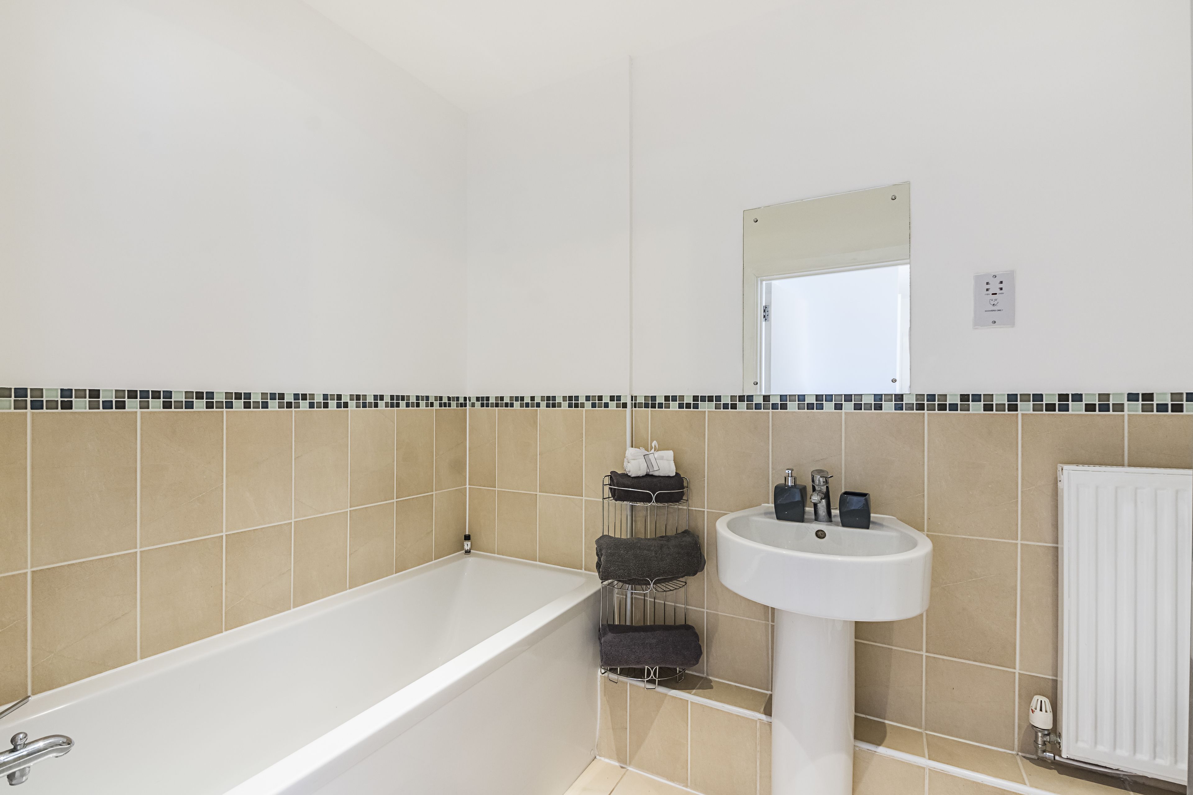 Een badkamer met een bad, een wastafel en een handdoekrek.