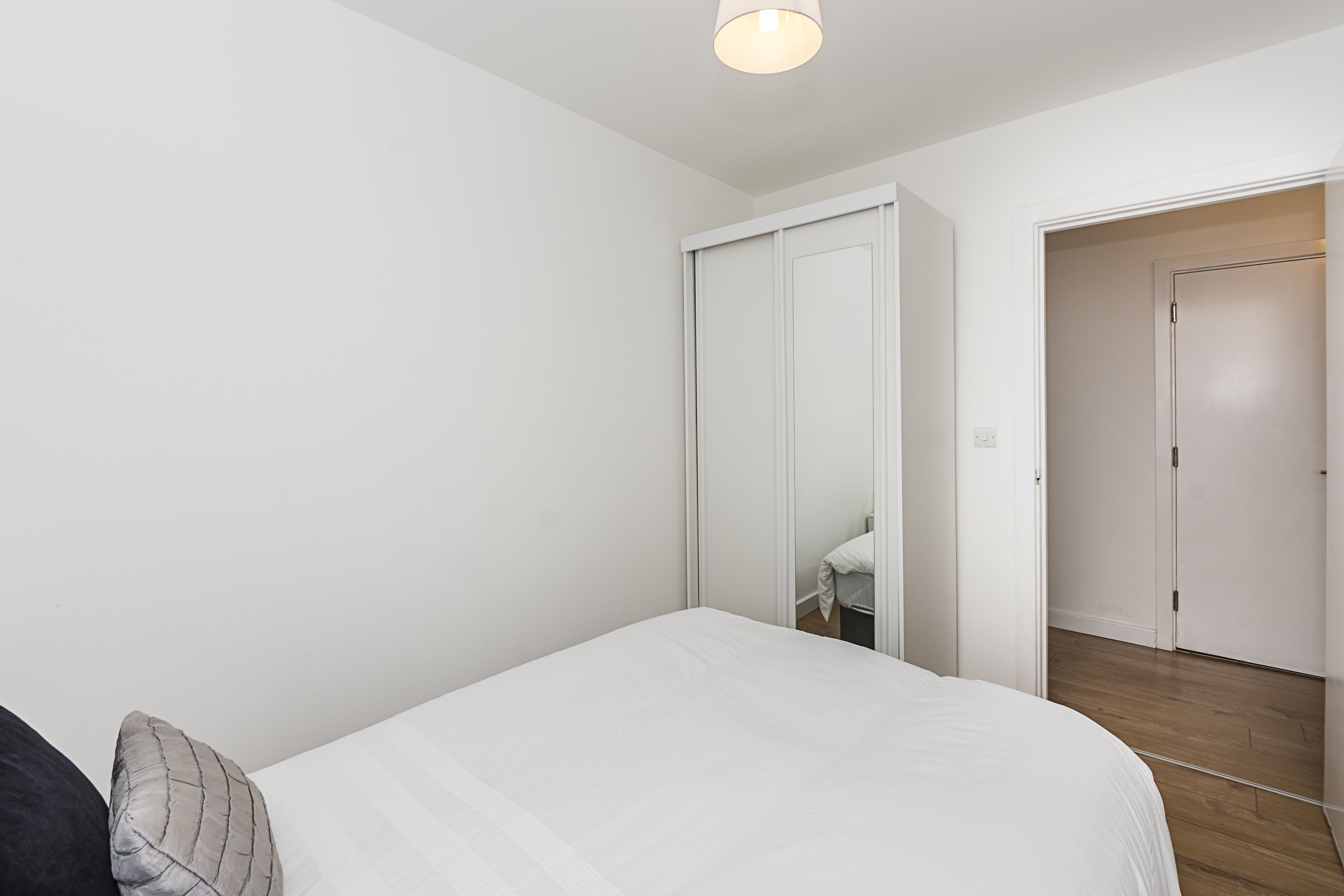 Een slaapkamer met een bed, een kledingkast en een deur naar een andere kamer.