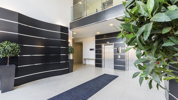 A modern lobby with a black and white color scheme, a central staircase, and a reception desk. - Heron House Apartments (Reading)