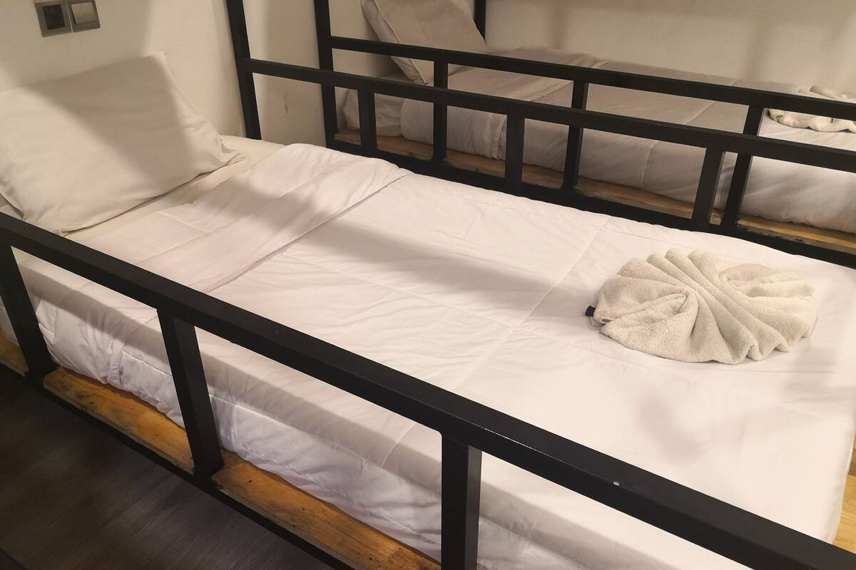 A single bed with a wooden frame and white bedding.