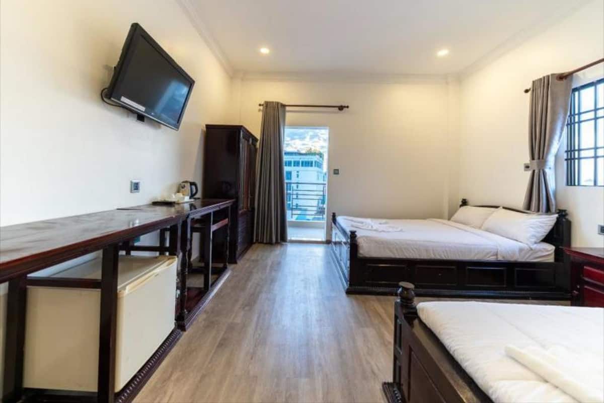 A compact hotel room with a bed, a desk, a television, and a view of the outside.
