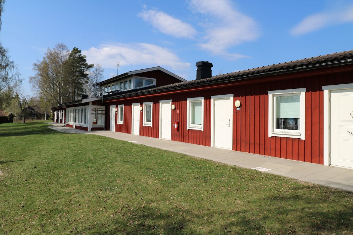 A row of red and white buildings with large windows and a clear sky.