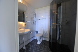 A modern bathroom with a white sink, toilet, and glass shower enclosure.