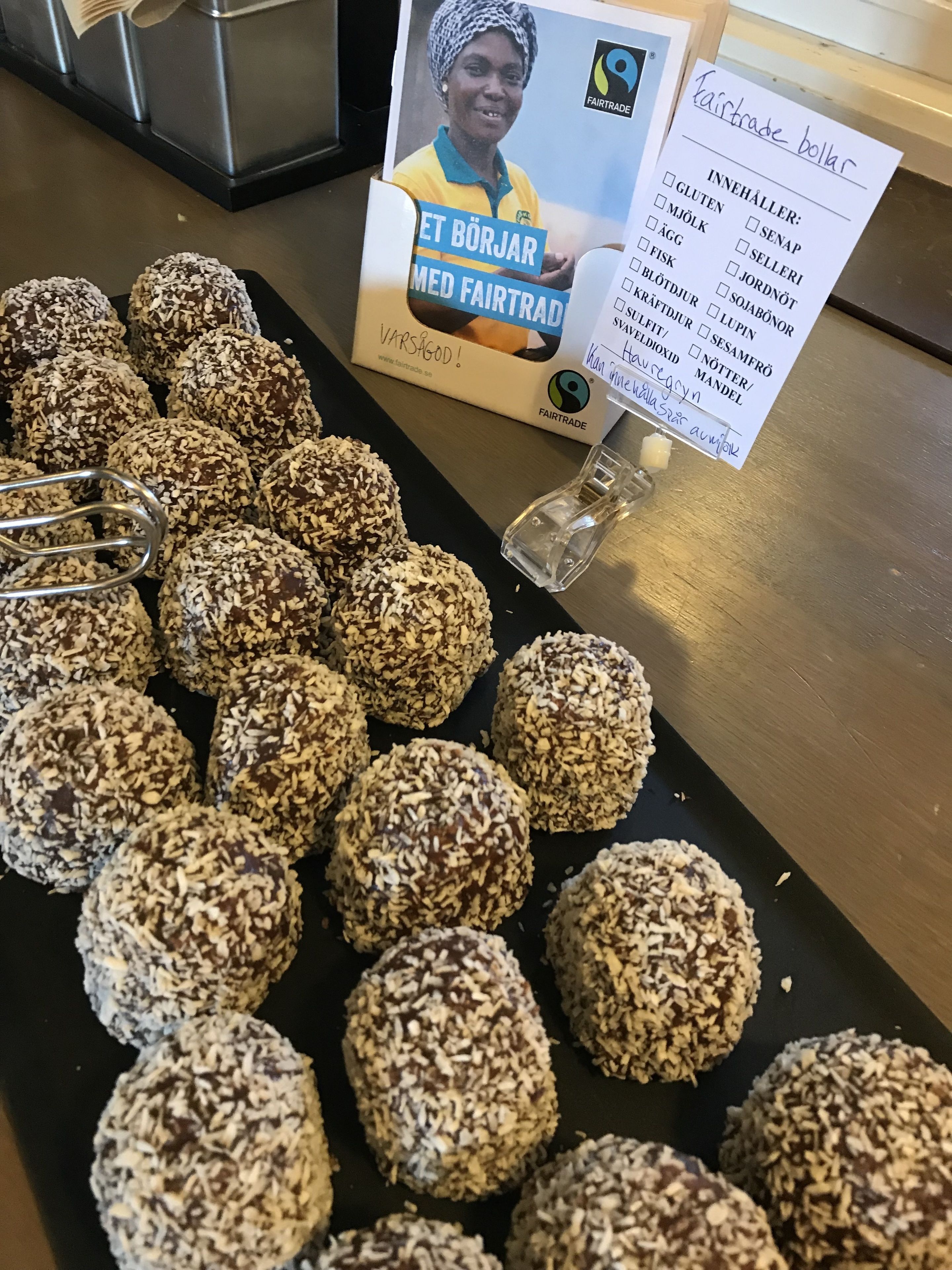Una bandeja de galletas de coco con etiqueta de comercio justo y una tarjeta de menú.