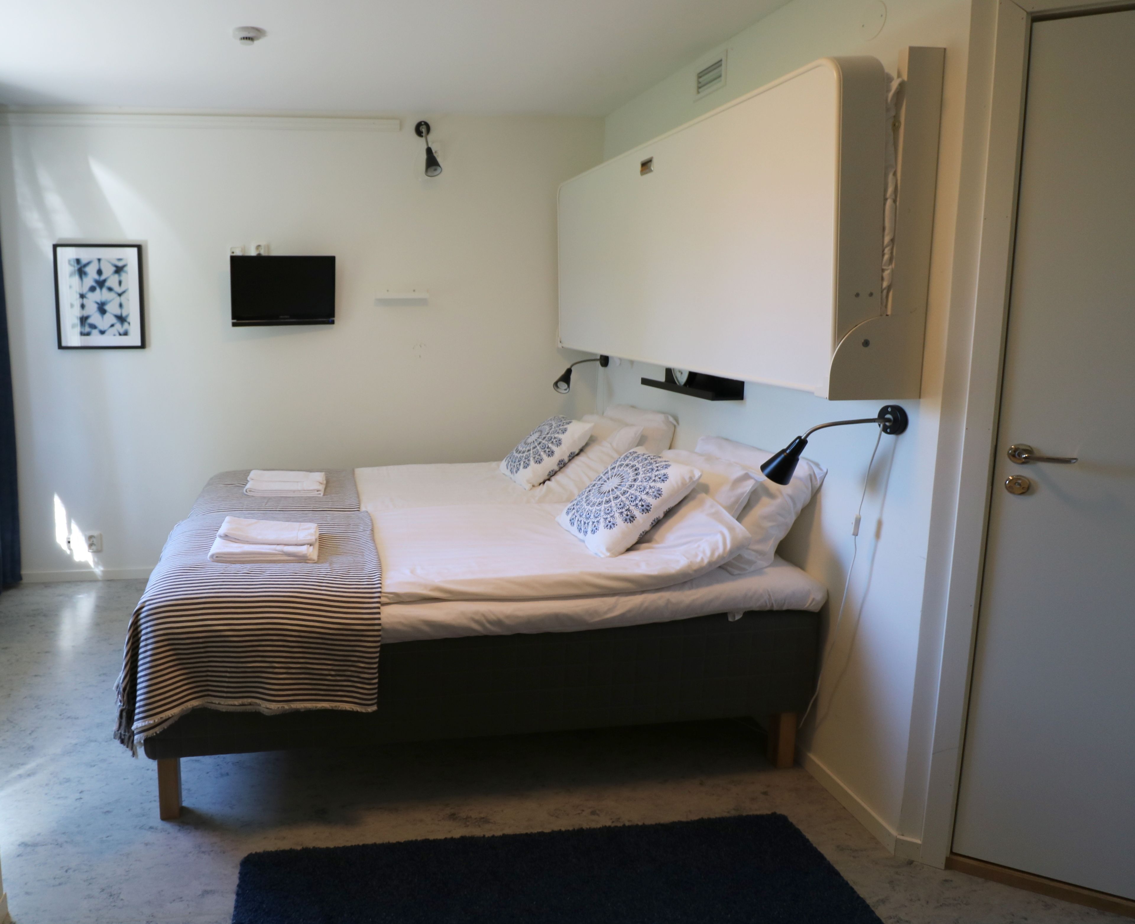 Un dormitorio con cama, lámparas de noche, televisor de pantalla plana y una puerta.
