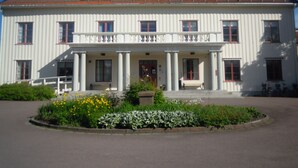 A large white building with a red-tiled roof, multiple windows, and a central entrance with columns.