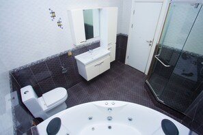 Un baño moderno con bañera, inodoro, tocador y cabina de ducha de vidrio.