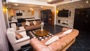 A modern living room with a sectional sofa, armchairs, a coffee table, and a TV mounted on the wall. - Nkrabea Royal Apartmento (Accra)