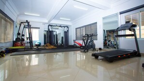 A spacious gym with various exercise equipment, large windows, and a polished floor. - Nkrabea Royal Apartmento (Accra)