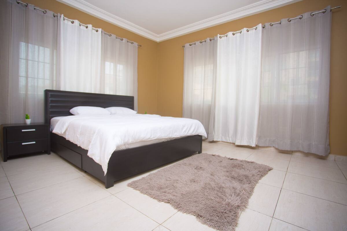 A bedroom with a bed, nightstand, and a fluffy rug.