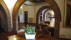 A dining area with a wooden table and chairs, a potted plant, and brick arches. - Verdidea - Il Tinaio (Monteroni d'Arbia)
