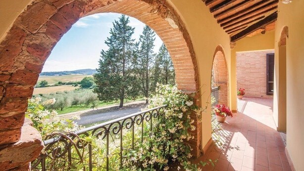 A balcony with a brick archway, a metal railing, and potted plants. - Verdidea - Il Tinaio (Monteroni d'Arbia)