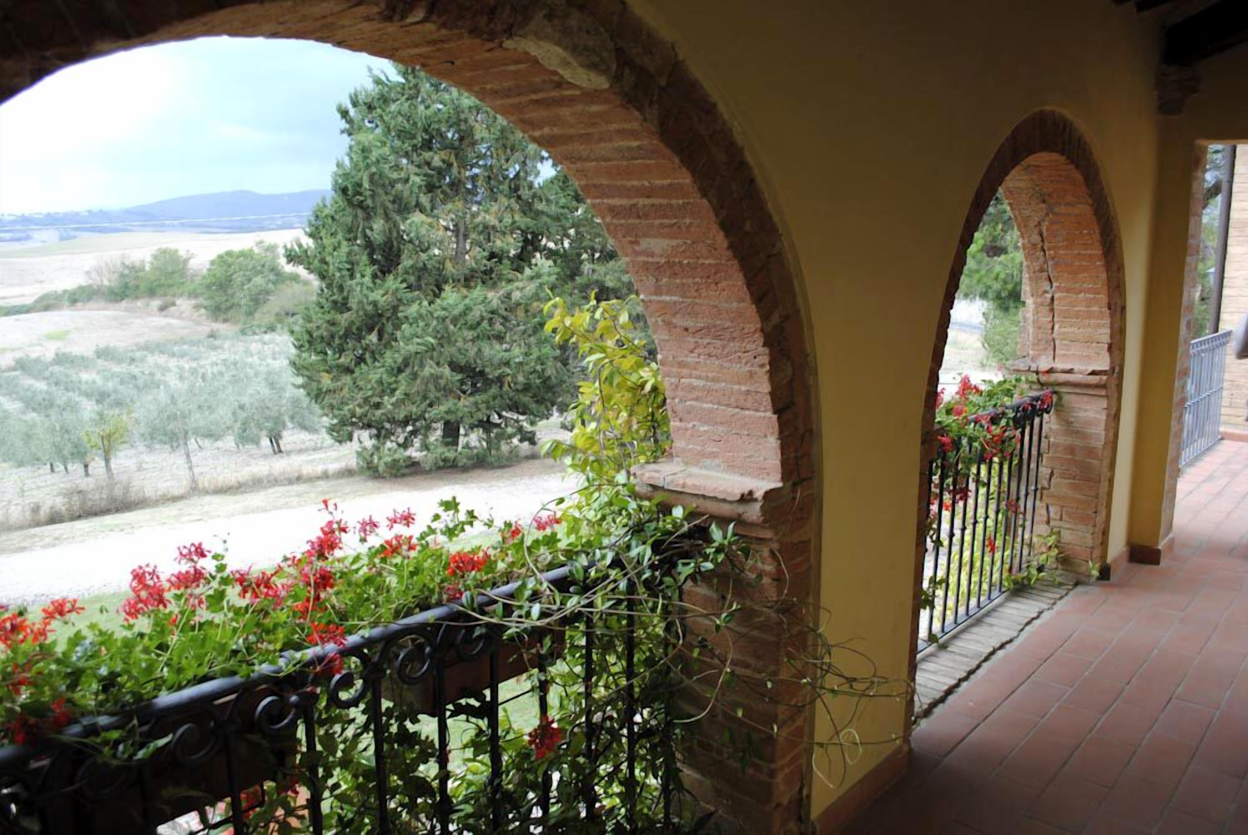 A balcony with a view of a rural landscape, featuring trees and a clear sky.