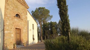 Un edificio con fachada de piedra y pared blanca, una puerta de madera y un camino de grava que lleva a él.