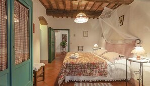Een gezellige slaapkamer met een bed, een stoel, een nachtkastje en een hanglamp.