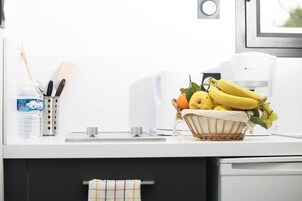 Una encimera de cocina con un cesto de plátanos, una botella de agua y utensilios de cocina.