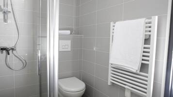 Um banheiro moderno com box de vidro, vaso sanitário branco e toalheiro com toalha branca.