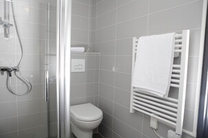 Um banheiro moderno com box de vidro, vaso sanitário branco e toalheiro com toalha branca.