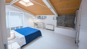 Een slaapkamer met een bed, een bureau, een stoel, een radiator en een bad.