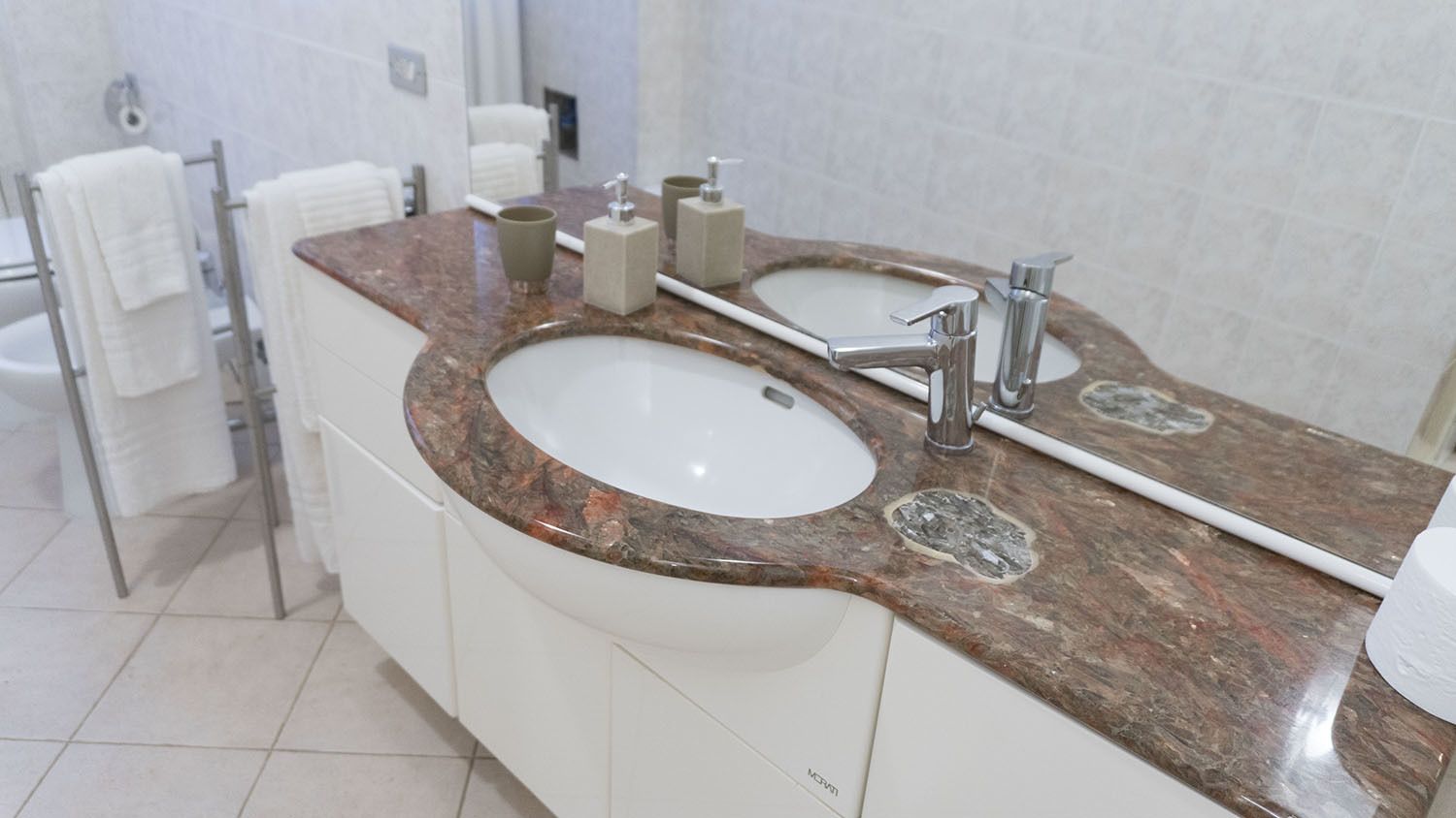 A bathroom with a double sink vanity, white cabinets, and a marble countertop.