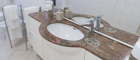 A bathroom with a double sink vanity, white cabinets, and a marble countertop.
