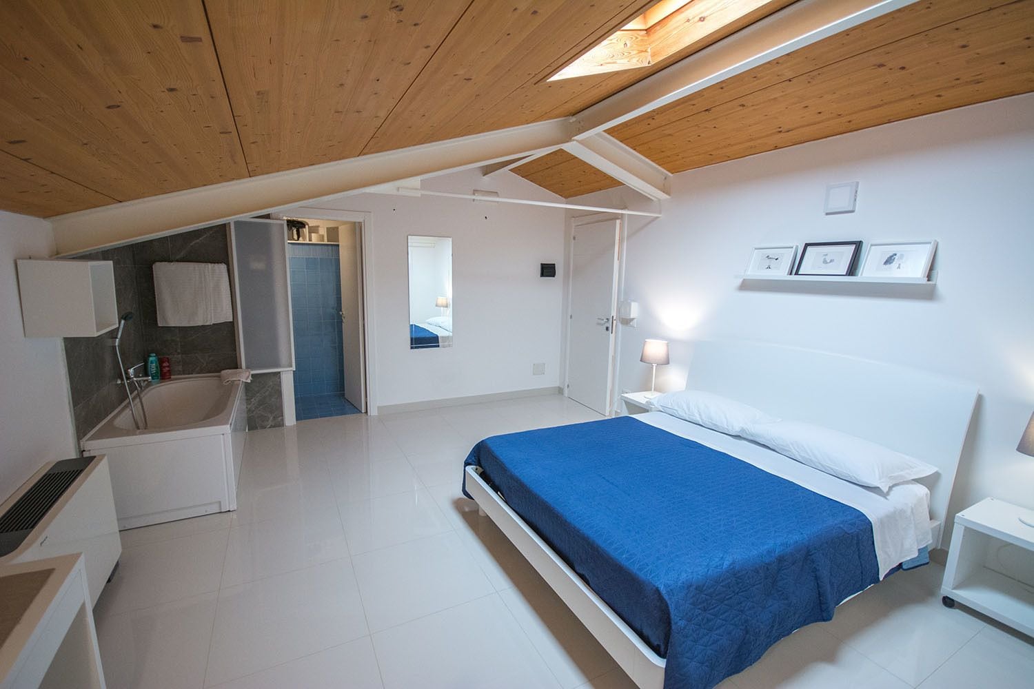 A modern bedroom with a bed, bedside table, and a mirror.
