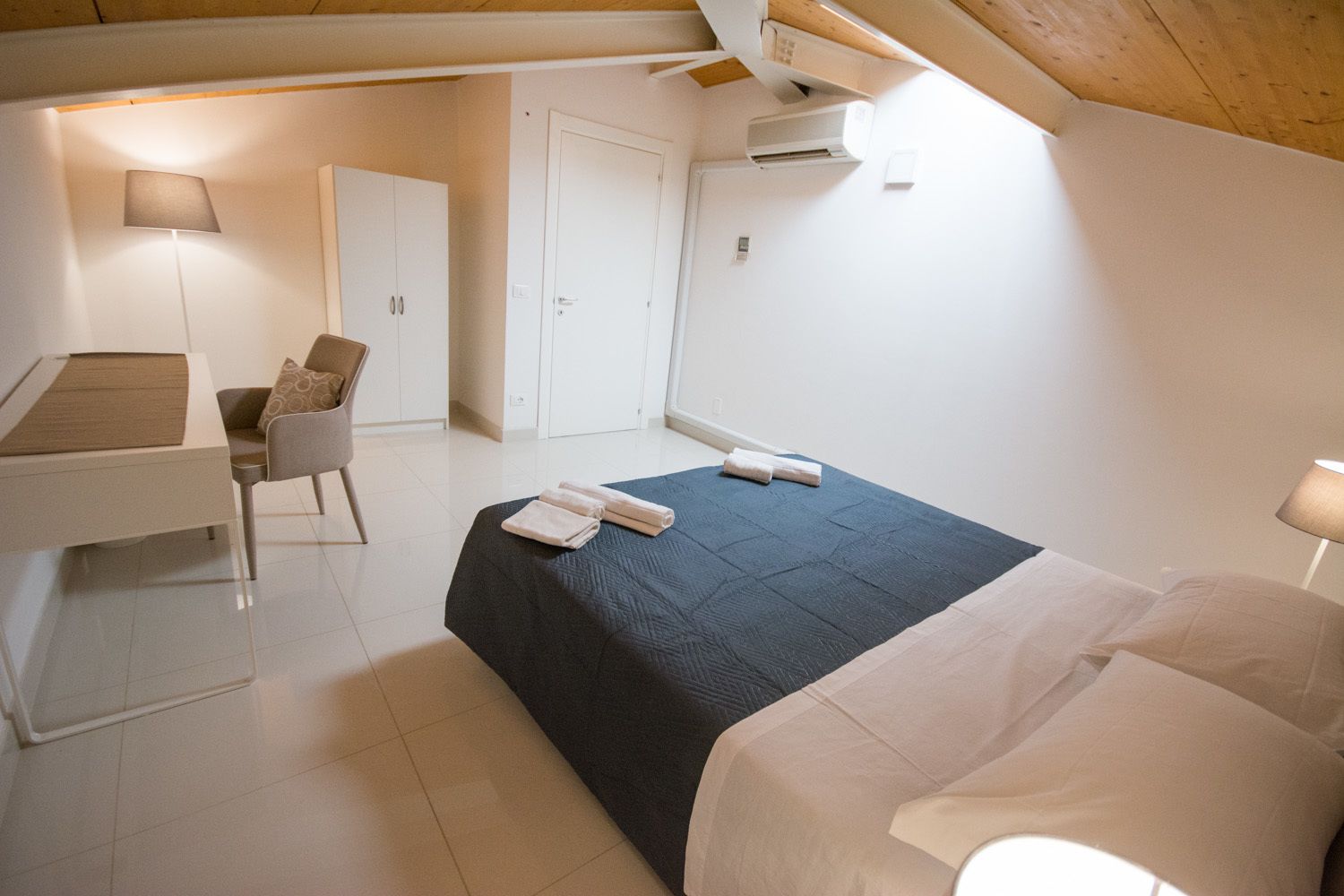 Un dormitorio con cama, escritorio, silla y armario.