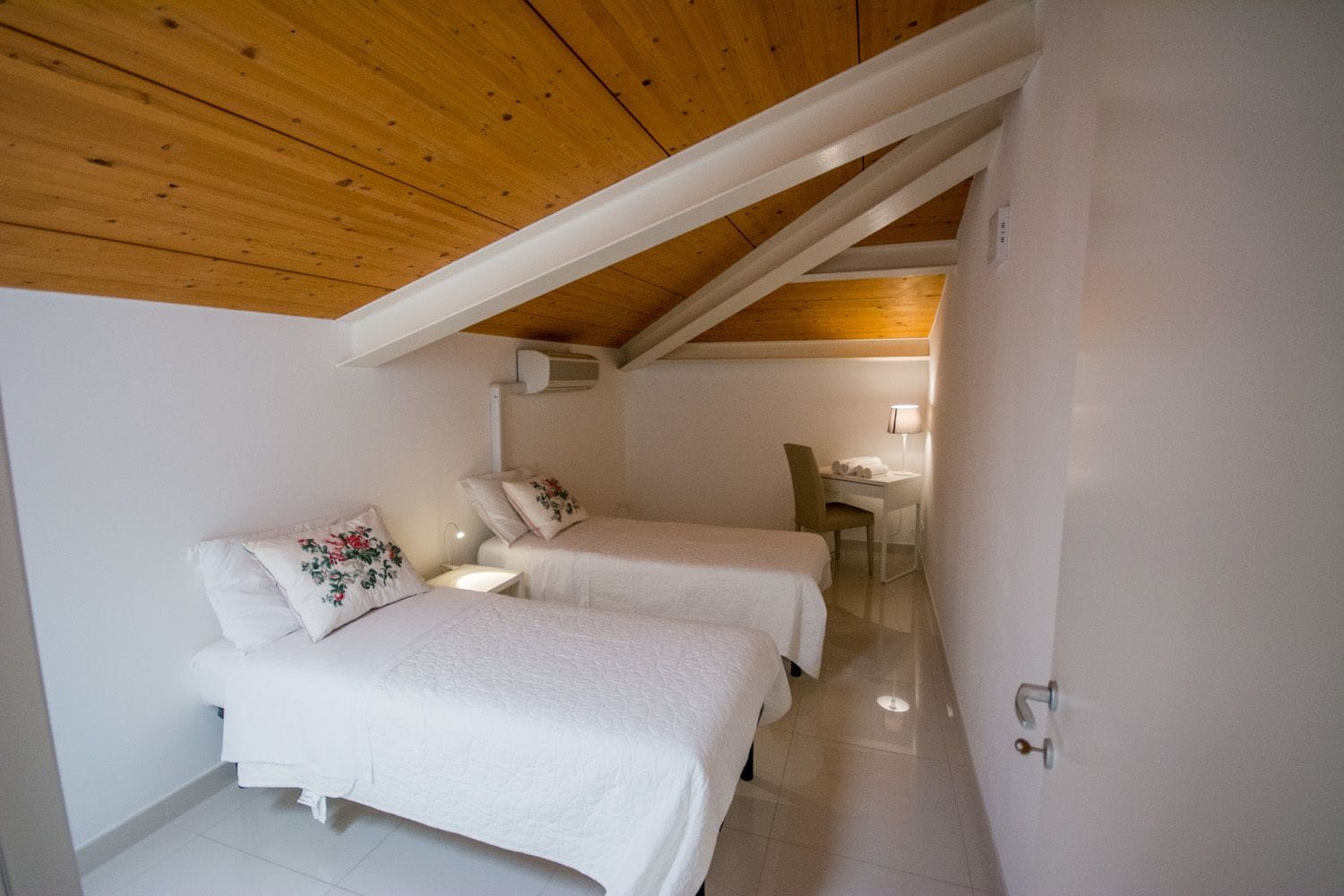 Una habitación pequeña y acogedora con dos camas individuales, un escritorio y una silla.