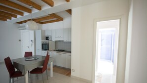 Een moderne keuken met witte kasten, een eettafel met rode stoelen en een zichtbare oven.