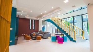Amplia sala de estar con una escalera moderna, un conjunto de sofás y otomanas de colores.