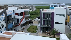 Un moderno complejo de apartamentos con varios balcones, un pequeño patio interior y vistas del entorno.
