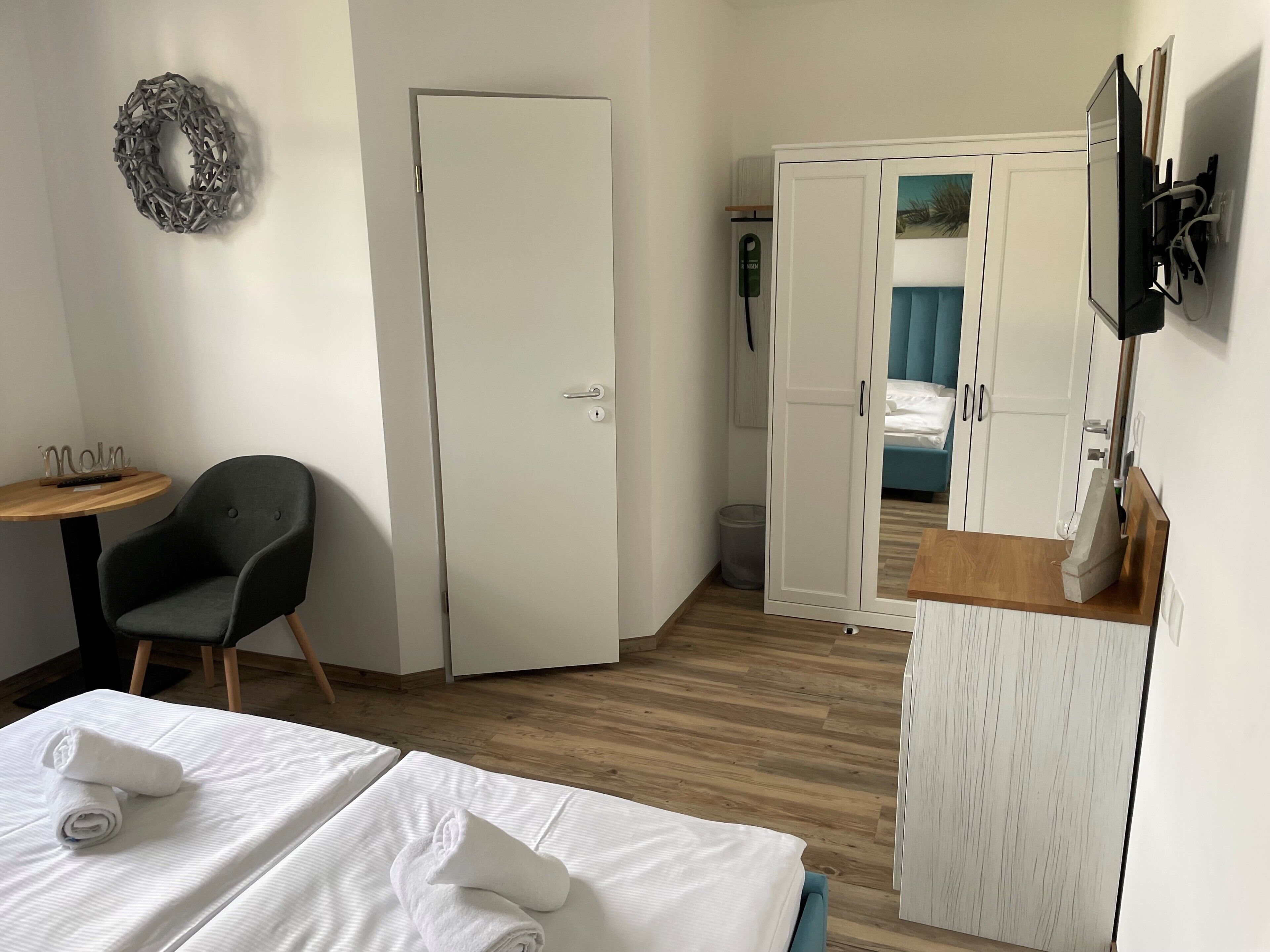 A hotel room with a bed, a desk, a chair, a wardrobe, and a TV.