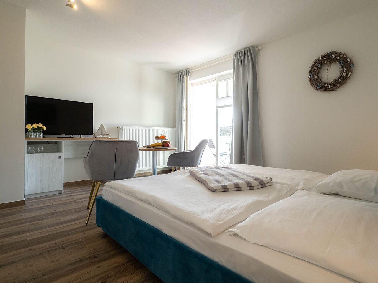 Een hotelkamer met een groot bed, een bureau met een televisie, een stoel en een raam met gordijnen.