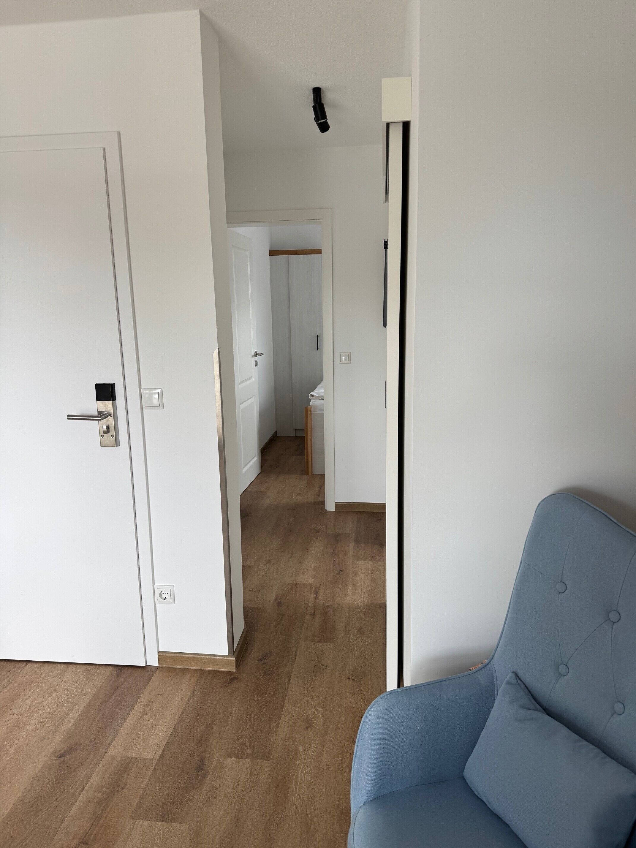 A room with a wooden floor, a blue chair, and white walls.