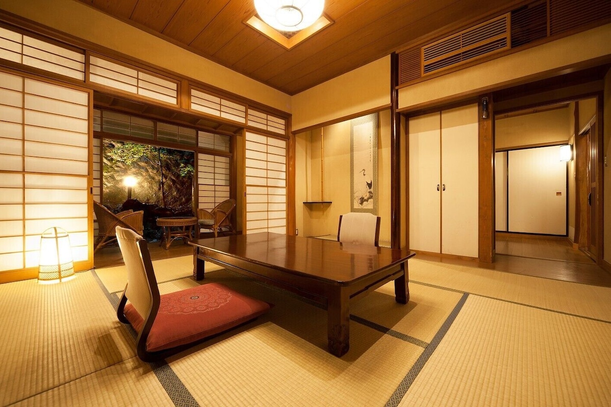 Une pièce de style japonais traditionnel, avec un sol recouvert de tatamis, une table basse et des portes coulissantes.